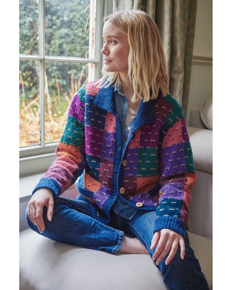 May include: A colorful patchwork cardigan with a button closure. The cardigan is made of a soft, textured yarn and features a variety of colors, including pink, purple, green, orange, and blue.