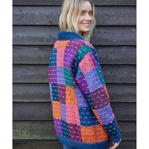 May include: A colorful patchwork cardigan with a blue base and squares of pink, orange, purple, and green. The cardigan is knitted and has a relaxed fit.