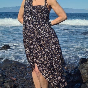 May include: A black and white patterned sarong with a swirling design. The sarong is worn as a dress and has a side slit.