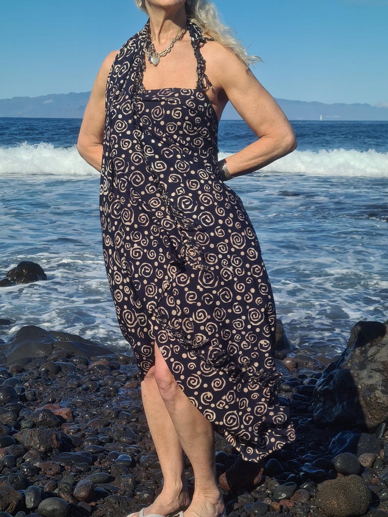 May include: A black and white patterned sarong with a swirling design. The sarong is worn as a dress and has a side slit.