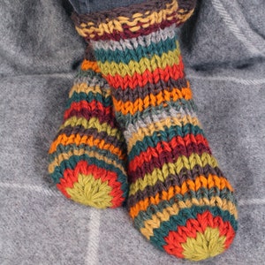 May include: A pair of colorful striped knitted socks with a brown cuff. The socks are made of wool and have a variety of colors, including red, orange, yellow, green, blue, and brown.
