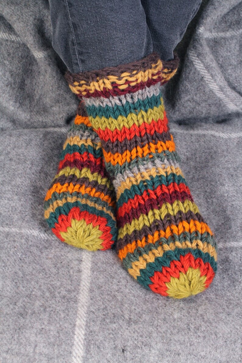 May include: A pair of colorful striped knitted socks with a brown cuff. The socks are made of wool and have a variety of colors, including red, orange, yellow, green, blue, and brown.