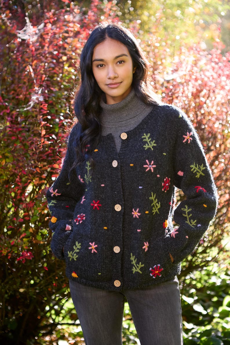 May include: A dark gray cardigan with embroidered flowers in shades of pink, red, yellow, and green. The cardigan has a button-up front and long sleeves.
