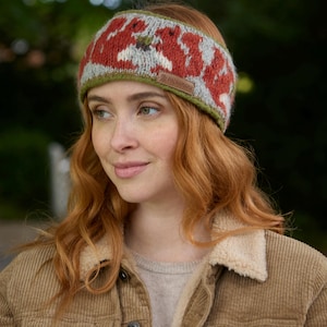 May include: A woman wearing a brown corduroy jacket with a fleece lining and a red and grey knit headband with a squirrel design. The headband has a small brown label with the text "Pachamama" on it.
