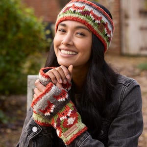 May include: A woman wearing a red, green, and white knit headband with a fox pattern and matching fingerless gloves. The headband and gloves have a brown, gray, and white knit pattern.
