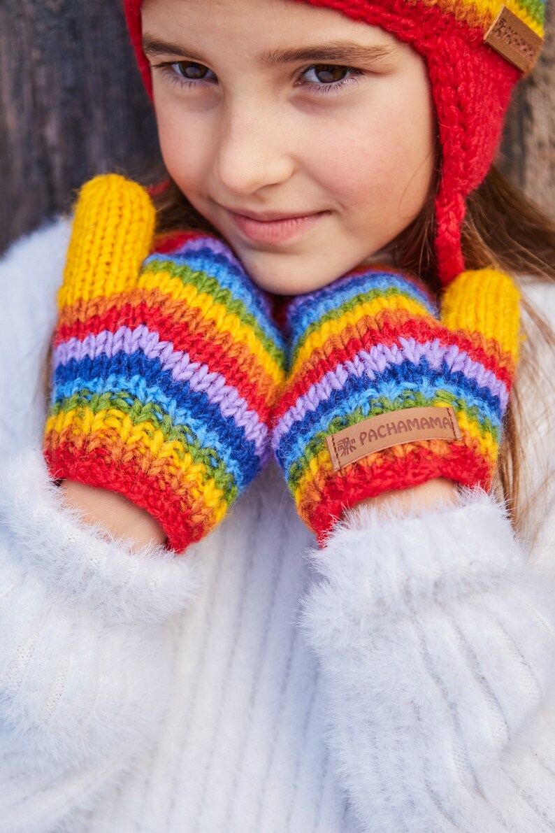 May include: A pair of rainbow striped knitted mittens with a brown leather tag that says "Pachamama".