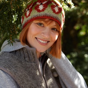May include: A woman wearing a gray hooded sweater and a red, green, and white knit hat with a fox design. The hat has a red brim and a green and white pattern.