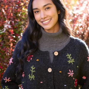 May include: A black knitted cardigan with colorful floral embroidery. The cardigan has a mock neck and button closure.