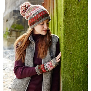 Puede incluir: Una mujer con un chaleco gris y marrón, un gorro de punto con estampado rojo, verde y blanco y guantes sin dedos a juego.
