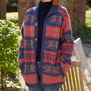 Peut inclure: Un cardigan bleu en tricot avec un motif géométrique coloré représentant des oiseaux et des feuilles. Le cardigan a une fermeture à boutons et des poches.