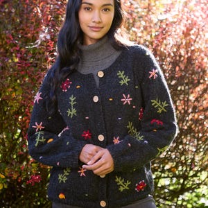 May include: A dark gray cardigan with embroidered flowers in shades of pink, red, yellow, and green. The cardigan has a button closure and long sleeves.