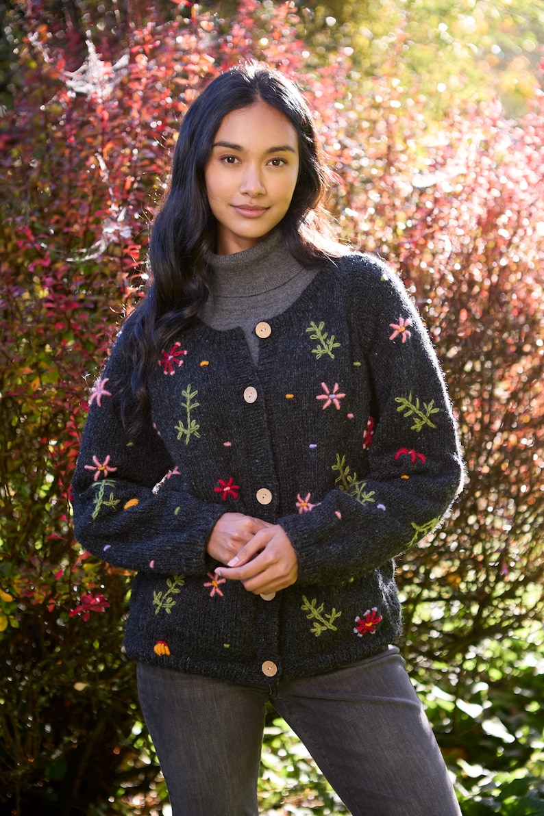 May include: A dark gray cardigan with embroidered flowers in shades of pink, red, yellow, and green. The cardigan has a button closure and long sleeves.