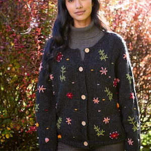 May include: A dark gray cardigan with embroidered flowers in shades of pink, red, yellow, and green. The cardigan has a button-up front and long sleeves.