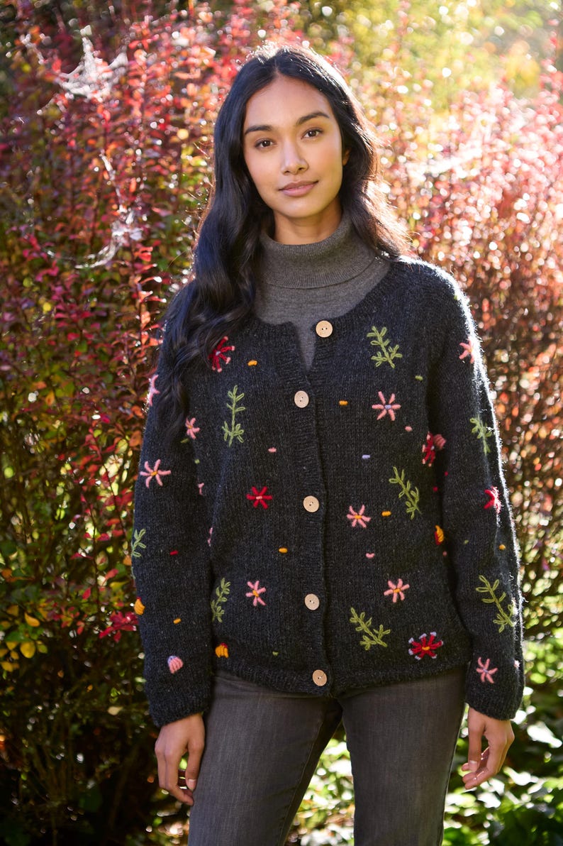 May include: A dark gray cardigan with embroidered flowers in shades of pink, red, yellow, and green. The cardigan has a button-up front and long sleeves.