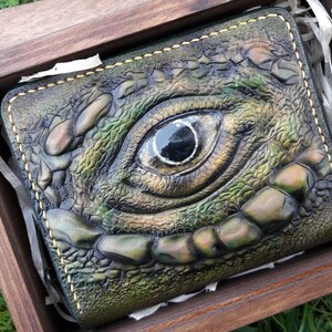 Pequeña cartera de cuero con cremallera, decorada con un ojo de reptil.