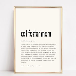 Könnte beinhalten: Ein gerahmter Druck mit den Worten "cat foster mom" in fetter schwarzer Schrift. Die Definition einer Katzenpflegemutter steht unter dem Titel in kleinerer schwarzer Schrift. Der Rahmen ist goldfarben.