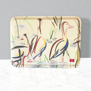 May include: Cream-coloured rectangular serving tray with a painted design of ducks in a marsh. The ducks are depicted with red, black, yellow, and blue details. Green reeds and water are also shown.