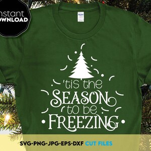 Op de afbeelding: Donkergroen t-shirt met een witte kerstboomafbeelding en de tekst "'tis the SEASON to be FREEZING." Inclusief "Instant DOWNLOAD" en bestandsinfo. Het shirt is van het merk Gildan.