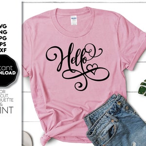 May include: A pink t-shirt with the word "Hello" written in black cursive with a heart at the end of the word.