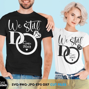 Könnte beinhalten: Zwei weiße T-Shirts mit schwarzem Text und einem Ringdesign. Der Text auf den Shirts lautet "We Still Do" mit dem Jahr "2012" im Ringdesign.