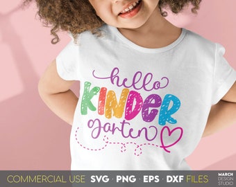 Könnte beinhalten: Ein weißes T-Shirt mit dem Text "hello kindergarten" in bunten, strukturierten Buchstaben. Ein rosa Herz befindet sich neben dem Text. Das Shirt wird von einem Kind mit lockigem braunen Haar getragen.