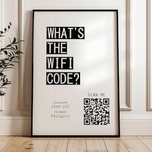 May include: A framed black and white print with the text "WHAT'S THE WIFI CODE?" in bold, sans-serif font. Below, it displays the username "eXam-p1E" and password "P4ssWoRD". A QR code is present, with the words "SCAN ME" above it.