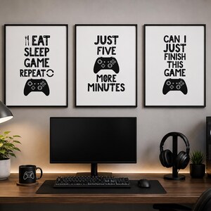 Puede incluir: Tres l&aacute;minas de pared enmarcadas con fondos blancos y texto negro. La primera dice EAT SLEEP GAME REPEAT con un icono de mando. La segunda dice JUST FIVE MORE MINUTES con un mando. La tercera dice CAN I JUST FINISH THIS GAME.