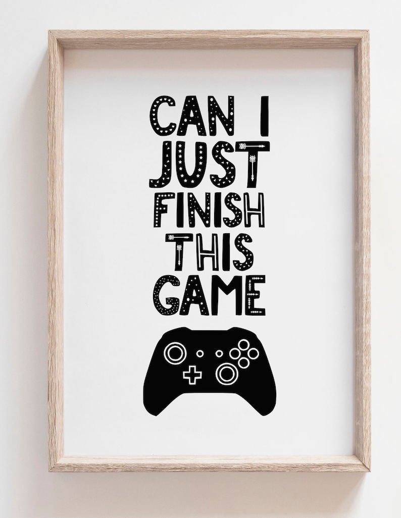 Puede incluir: Una l&aacute;mina enmarcada con el texto negro CAN I JUST FINISH THIS GAME en una fuente decorativa con detalles de flechas y estrellas. Debajo del texto hay una silueta negra s&oacute;lida de un mando de videojuegos sobre un fondo blanco.