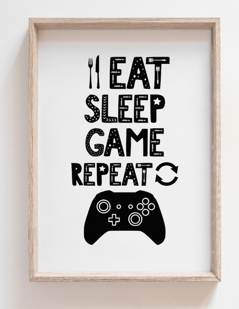 Puede incluir: Una l&aacute;mina enmarcada con el texto negro I EAT SLEEP GAME REPEAT, junto a un icono de tenedor y cuchillo, una estrella y un s&iacute;mbolo de flecha circular. Debajo del texto aparece la silueta negra de un mando de videojuegos sobre fondo blanco.