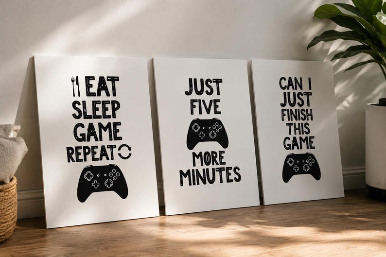 Puede incluir: Un conjunto de tres l&aacute;minas rectangulares blancas para pared con texto y gr&aacute;ficos en negro. La primera l&aacute;mina dice EAT SLEEP GAME REPEAT con un tenedor y un mando de juego. La segunda dice JUST FIVE MORE MINUTES con un mando. La tercera dice CAN I JUST FINISH THIS GAME con un mando.