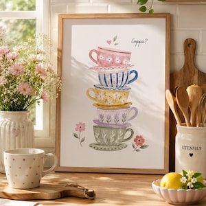 May include: A framed wall art print featuring a vertical stack of five colourful, patterned teacups and saucers in shades of pink, blue, yellow, lavender, and green, with the text "Cuppa?" written in black script near the top right corner.