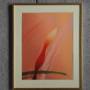 May include: A framed abstract art print with a red and orange abstract shape on a pink background. The print is in a gold frame.