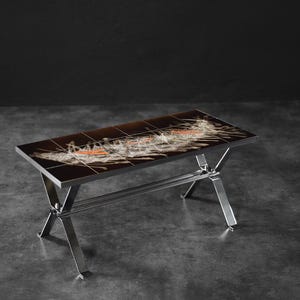 May include: A rectangular coffee table with a dark brown, patterned top and a chrome-coloured metal frame. The table's top features a design with white and orange accents. The table is approximately 122 cm long and 61 cm wide.