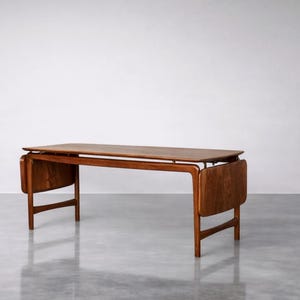 Puede incluir: Un escritorio de madera de estilo moderno de mediados de siglo con una parte superior rectangular y dos extensiones abatibles. El escritorio está hecho de madera de tonos cálidos y tiene un diseño minimalista. El escritorio mide aproximadamente 152 cm de largo.