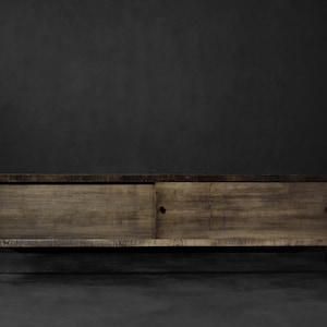 May include: A dark brown wooden cabinet with two sliding doors and black metal legs. The cabinet is sitting on a gray concrete floor.