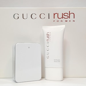 May include: A Gucci Rush for Men gift set featuring a white rectangular fragrance bottle and a white shower gel tube. The set is presented in a large white box with the text Gucci Rush for Men printed in dark red lettering on the front surface.