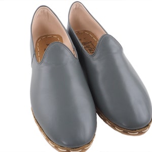 Peut inclure: Une paire de chaussures en cuir gris &agrave; enfiler avec une semelle marron et des coutures blanches.