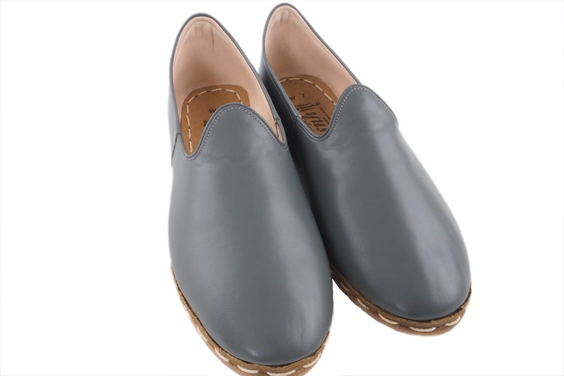 Peut inclure: Une paire de chaussures en cuir gris &agrave; enfiler avec une semelle marron et des coutures blanches.