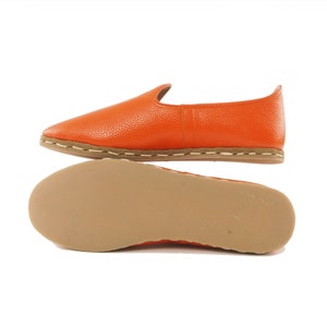 May include: Orange leather slip-on shoes with a brown sole and white stitching.