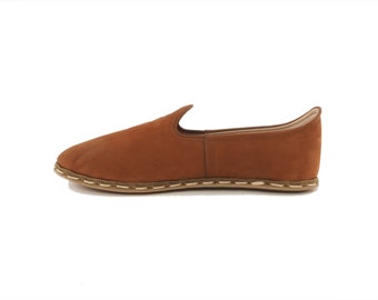 May include: A pair of brown leather slip-on shoes with a white stitch detail around the sole.