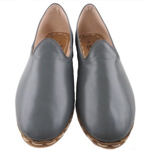 Peut inclure: Une paire de chaussures &agrave; enfiler en cuir gris avec un bord cousu autour de la semelle.