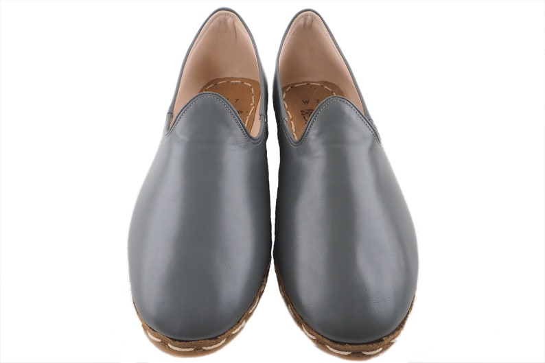 Peut inclure: Une paire de chaussures &agrave; enfiler en cuir gris avec un bord cousu autour de la semelle.