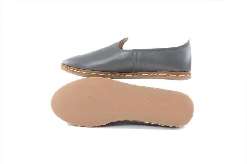 Peut inclure: Chaussures en cuir gris &agrave; enfiler avec une semelle en cuir marron et des coutures sur le bord.