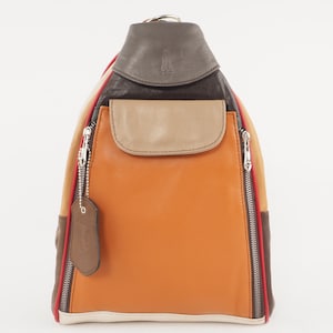 May include: A multi-colored leather backpack with a zippered pocket on the front. The backpack is made of brown, tan, orange, and white leather. The zippers are silver and the stitching is red.