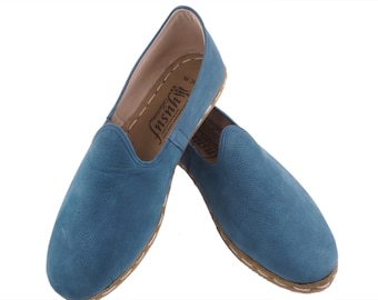 May include: A pair of blue leather slip-on shoes with a brown leather sole and a white stitching detail. The shoes have a brand label that says "Insuh" on the inside.