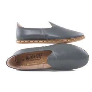 Peut inclure: Chaussures en cuir gris &agrave; enfiler avec une semelle marron et des coutures blanches. Les chaussures ont une pointe pointue et un talon bas. Le nom de la marque "Yusuf Collection" est imprim&eacute; sur la semelle int&eacute;rieure.