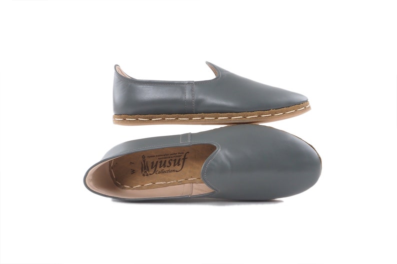 Peut inclure: Chaussures en cuir gris &agrave; enfiler avec une semelle marron et des coutures blanches. Les chaussures ont une pointe pointue et un talon bas. Le nom de la marque "Yusuf Collection" est imprim&eacute; sur la semelle int&eacute;rieure.