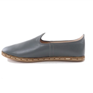 Peut inclure: Une paire de chaussures en cuir gris &agrave; enfiler avec une semelle cousue marron.