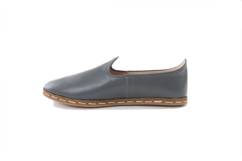 Peut inclure: Une paire de chaussures en cuir gris &agrave; enfiler avec une semelle cousue marron.