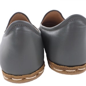 Peut inclure: Une paire de chaussures en cuir gris &agrave; enfiler avec une bordure cousue brune autour de la semelle.